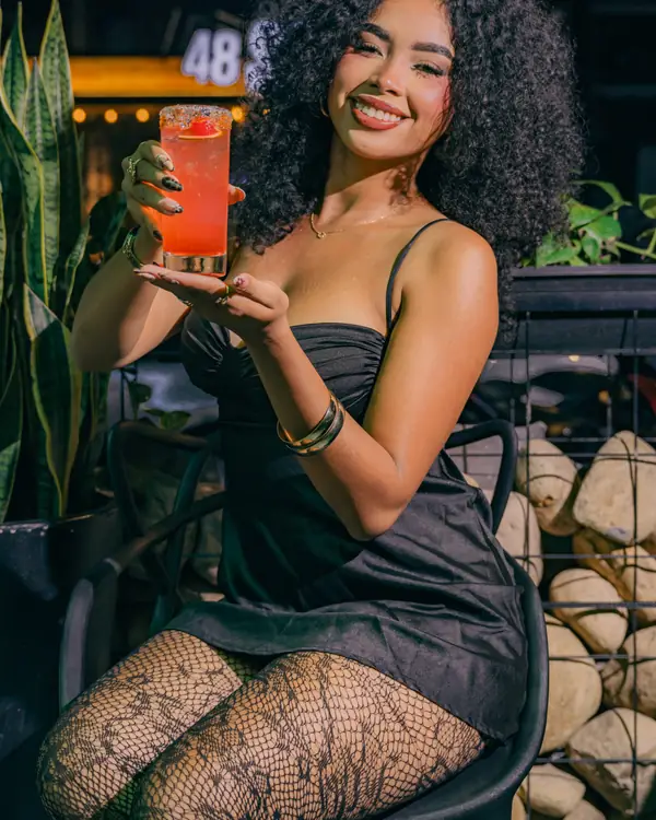 Invitada sonríe con su cóctel en la terraza de BKR48